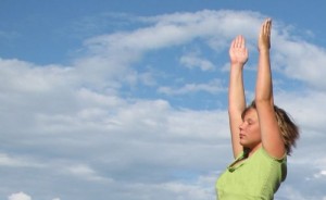 A teen is doing yoga with a beautiful blue sky in he background